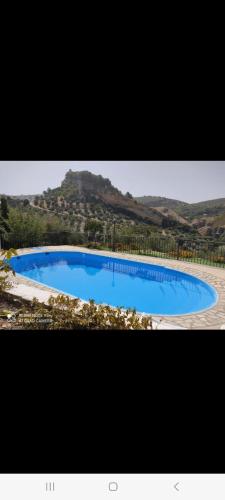 a large blue swimming pool in front of a mountain at Alojamiento rural El Yate in Montefrío