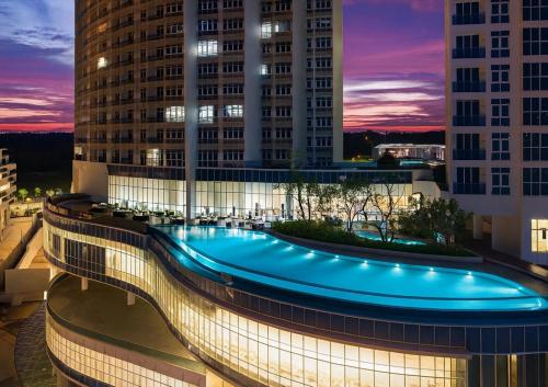 a large building with a swimming pool in the middle at UHF HOTELS and RESORTS PINETREE in Iskandar Puteri