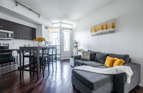 a living room with a couch and a table and a kitchen at 1 Bedroom plus Den Condo Garden View Fort York Downtown Toronto in Toronto