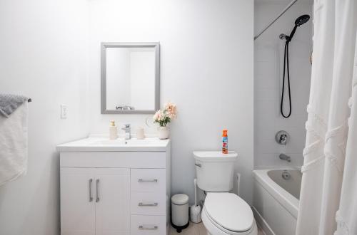 a bathroom with a toilet and a sink and a mirror at 1 Bedroom plus Den Condo Garden View Fort York Downtown Toronto in Toronto