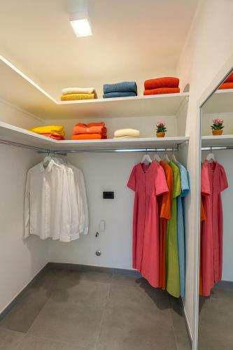 a walk in closet with colorful clothes on shelves at Casa Mimosa in Forio d'Ischia