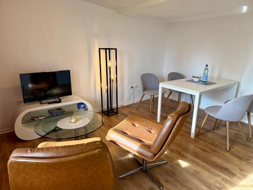 a living room with a table and a tv and chairs at Retro und Gemütlichkeit im Fachwerkhaus - 2 Schlafzimmer, Wohnzimmer, Parkplatz, Balkon in Wolfhagen