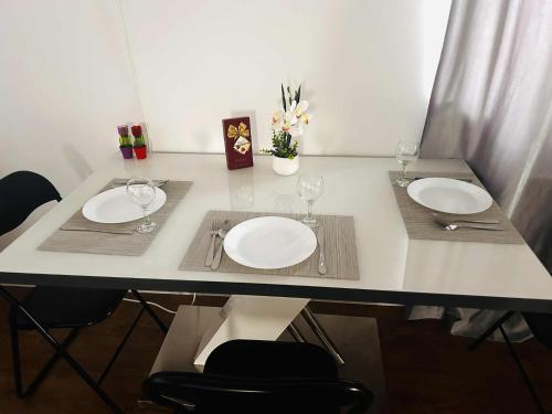 a table with two white plates and wine glasses at Apartament cu Terasă și Vedere la Apus in Voluntari