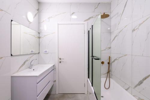 a white bathroom with a shower and a sink at Levication Premium Private Jacuzzi Apartments in Tiberias
