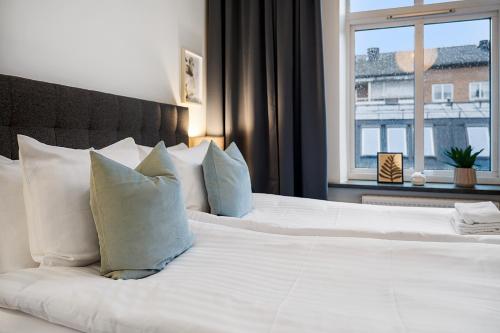 a bedroom with a white bed with pillows and a window at Amiralsgatan - City apartments in Malmö
