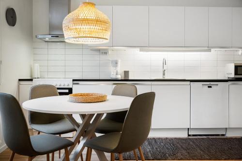 a white kitchen with a white table and chairs at Amiralsgatan - City apartments in Malmö