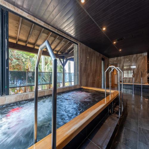 a hot tub in a room with a large window at Livemax Resort Inami Seafront in Inami