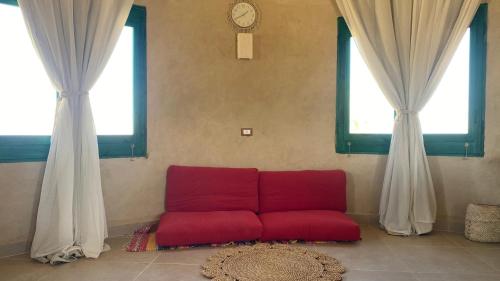 a red couch in a room with two windows at moon retreat in ‘Izbat Mushandid al Kabīrah