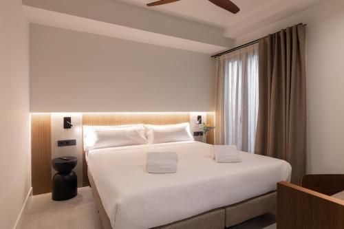 Un dormitorio con una gran cama blanca y una ventana. en Moontels Colón, en Valencia