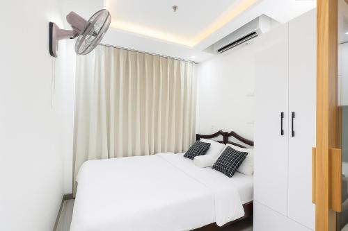 a bedroom with a white bed and a ceiling fan at Louis Luxury Apartment & Hotel in Danang