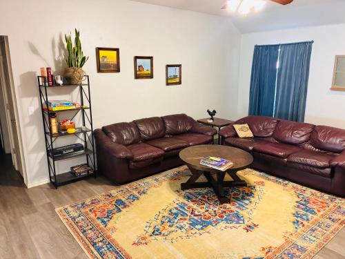 a living room with a brown leather couch and a table at Paradise on the Prairie in Oklahoma City