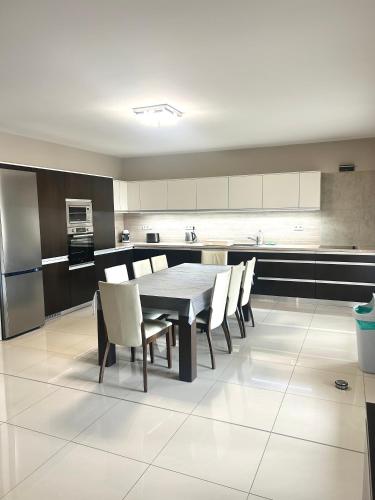 een keuken met een tafel, stoelen en een koelkast bij Vila Lexus in Veľký Meder