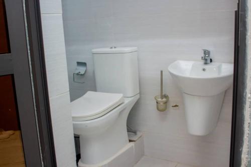 a white bathroom with a toilet and a sink at KapeView Elegant Suite in Cape Coast