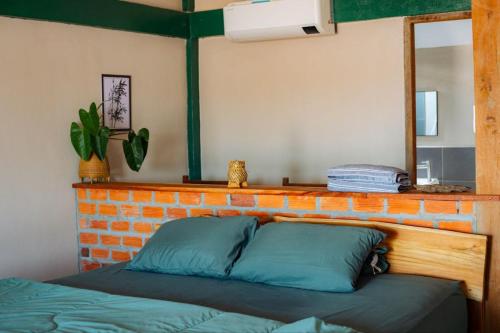 a bed in a room with a brick wall and a mirror at Don Falang Homestay- Private Island in Don Det