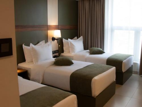 une chambre d'hôtel avec deux lits et une fenêtre dans l'établissement Coral Beach Hotel & Spa, à Aqaba