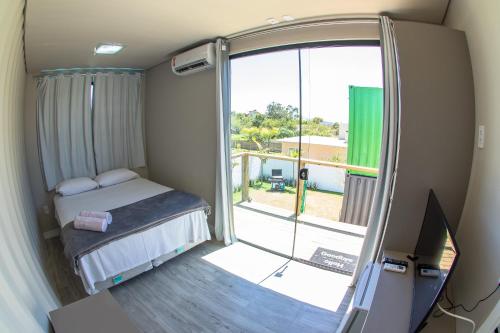 インビトゥバにあるInnbox Praia do Rosaの小さなベッドルーム(ベッド1台付)、スライド式ガラスドアが備わります。
