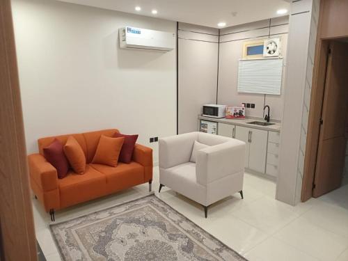 a living room with an orange couch and a white chair at فيلمست ريزيدنس ابها in Quai