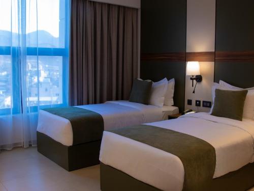 une chambre d'hôtel avec deux lits et une fenêtre dans l'établissement Coral Beach Hotel & Spa, à Aqaba