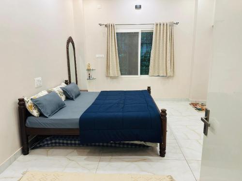 a bedroom with a bed with blue sheets and a window at Tranquil Farmstay by Vanaja Farms in Rāmanagaram