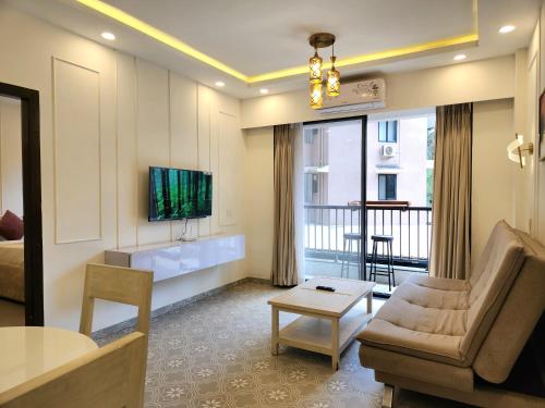 a living room with a couch and a table at Relaxed 1BHK Retreat - Pool, Balcony, Secure Parking, Walk to Candolim Beach in Candolim
