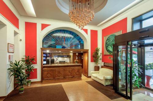 an office lobby with red walls and a chandelier at Hotel Oxford in Rome