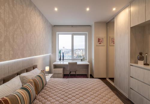 a bedroom with a bed and a desk and a window at Апартаменты с двумя спальнями с завораживающим видом на Днепр возле Мост Сити in Dnipro