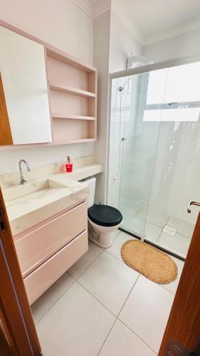 a bathroom with a toilet and a glass shower at Ap 2 Quartos 5km da BR, Palhoça in Palhoça