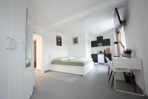 a white bedroom with a bed and a desk at Modernes Serviced Apartment Groß-Zimmern - Parkplatz in Groß-Zimmern