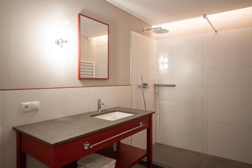 a bathroom with a sink and a shower at Vitalpina Hotel Schulerhof in Plaus