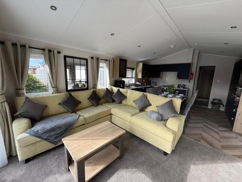 a living room with a large yellow couch with pillows at King Carp in Tattershall