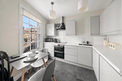 a kitchen with white cabinets and a table and chairs at Central Kings Cross modern house with free parking in London