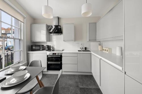 a kitchen with white cabinets and a table and chairs at Central Kings Cross modern house with free parking in London
