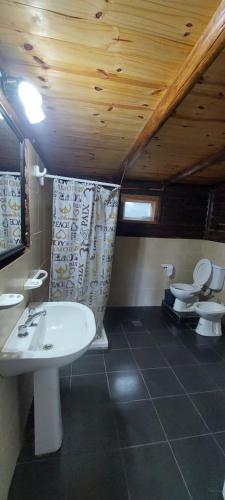 ein Badezimmer mit einem weißen Waschbecken und 2 WCs in der Unterkunft cabaña en el bosque in Valle Hermoso