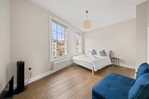 a living room with a blue couch and a bed at Central Kings Cross modern house with free parking in London