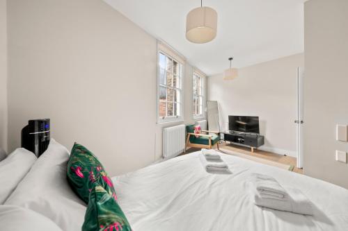 a large white bed in a room with a tv at Central Kings Cross modern house with free parking in London