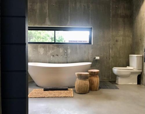 een badkamer met een bad, een toilet en een raam bij Bellevue on the Knysna lagoon in Knysna