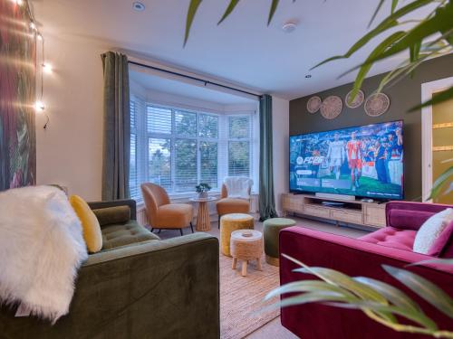 a living room with two couches and a flat screen tv at Oxford - hot tub, games room, parking, arcade in Oxford