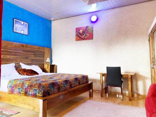 a bedroom with a bed and a desk and a chair at hotel confort by freeman in Palimé