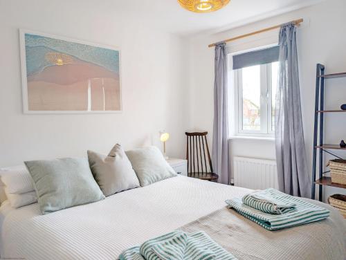 a bedroom with a white bed with a window at Sanderling House, with parking - walk to beach in Earnley