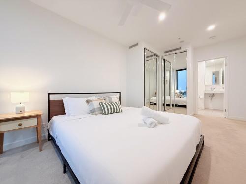 a white bedroom with a large bed and a desk at RiverView Breeze Hamilton 3B2B with Free Parking in Brisbane
