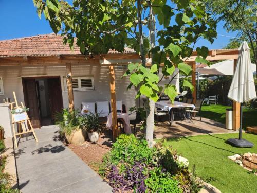 un patio con una mesa y una sombrilla en בית פרטי כפרי בהרצליה, en Herzelia 