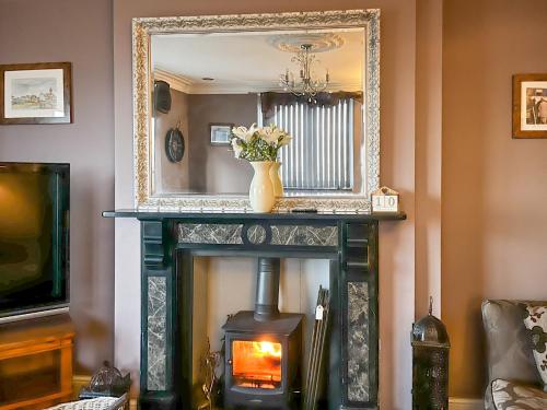 a fireplace in a living room with a mirror at The View Old Coastguard Cottage in Tynemouth