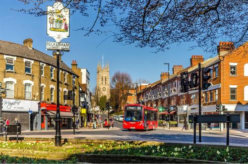 a red bus is driving down a city street at Spacious flat on the High St in Beckenham