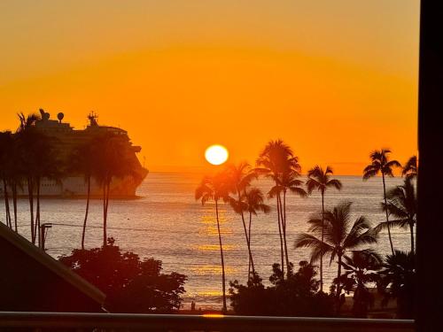 a cruise ship in the ocean at sunset with palm trees at Island Glow Kailua Village #508 free assigned parking, AC, downtown, walk to restaurants, bars and the pier in Kailua-Kona