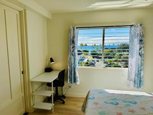a bedroom with a bed and a desk and a window at Island Glow Kailua Village #508 free assigned parking, AC, downtown, walk to restaurants, bars and the pier in Kailua-Kona