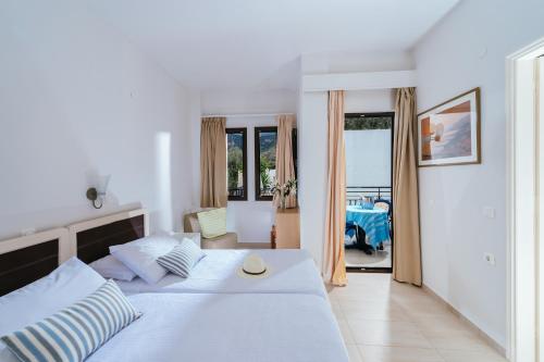 a bedroom with a large white bed and a table at Paradise Hotel-Apartments in Stalida