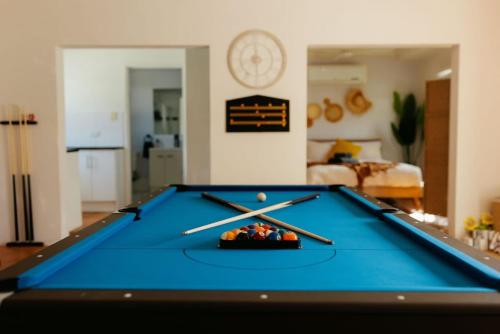 a pool table in a living room with two cuesticks at Seednest 7 bedroom beach house Pool &Game Room in Kewarra Beach