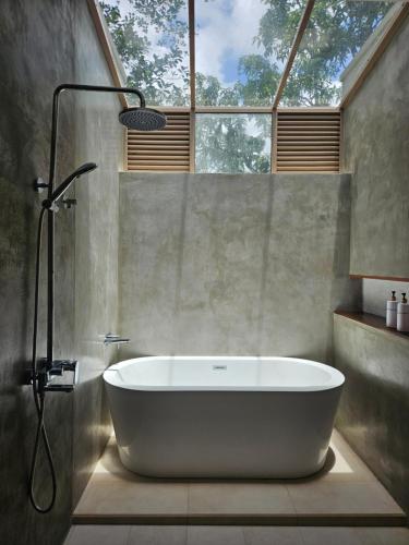 a bath tub in a bathroom with a window at ONA Garden Villa in Galgamuwa
