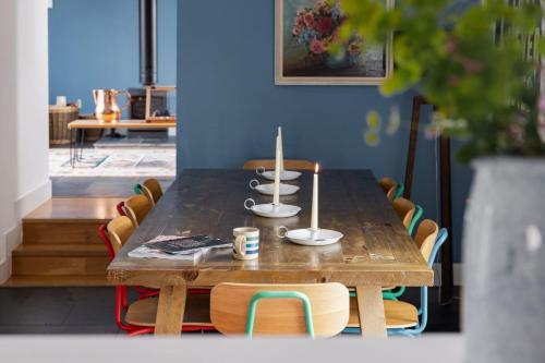 ein Holztisch mit Stühlen und ein Tisch mit Tassen darauf in der Unterkunft Cairn Cottage By Birch Stays in Stonehaven