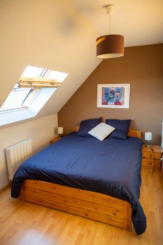 a bedroom with a bed with blue sheets and two skylights at Gite de la route du blé in Alluyes